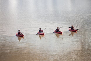 A line of kayakers paddle across the serene waters at the base of the Solheimajokull glacier.