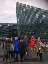 Группа людей во время пешеходной экскурсии стоит у концертного зала Harpa.