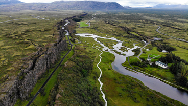 A bird view of the beautiful Thingvellir national park, seen with its white houses, flowing rivers and tectonic formations.