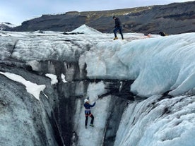 ソルヘイマヨークル氷河でアイスクライミングをする2人と背景の山々。
