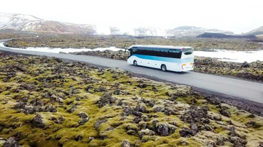 A bus from the Blue Lagoon to Reykjavik passing scenic moss-covered lava fields in Iceland.