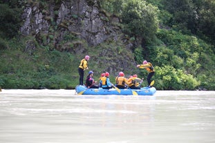 Eine Gruppe auf einem Floß im Fluss Hvita, an jedem Ende steht eine Person aufrecht.
