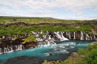 Beautiful view of Hraunfossar in West Iceland, where waterfalls pour through lava rocks into a blue river.