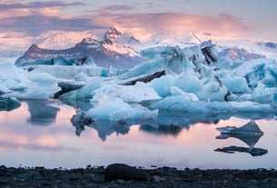 Icebergs float peacefully at sunset in the Jokulsarlon Glacier Lagoon, with Vatnajokull glacier in the background.
