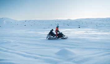 Snowmobile adventure on Langjokull Glacier in Iceland with a guide and guest in winter gear.