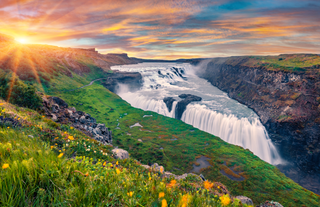 The Gullfoss waterfall cascades dramatically into a rugged canyon on a summer sunset in Iceland's Golden Circle.