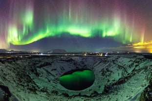 The northern lights dance above the Kerid Crater and its frozen lake in South Iceland on a clear winter night.