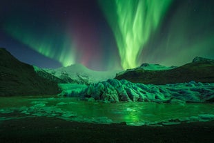 Aurora borealis dances above Vatnajokull Glacier in Southeast Iceland, lighting up the frozen landscape.