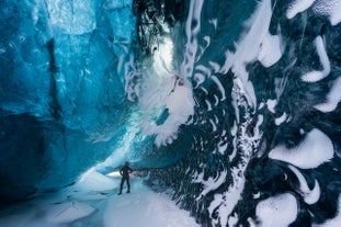 A person explores a stunning blue ice cave in Vatnajokull glacier, South Coast of Iceland, during winter.