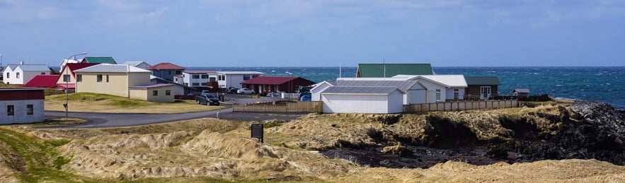 Coastal houses in Hellissandur overlooking the ocean and rocky shoreline.